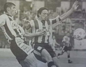 El primer partido del historial en 1999: Atlanta 1 -Tristán Suárez 0, en Villa Crespo, único triunfo bohemio sobre el Lechero en el Gran León. Aquí, Alberto Bernabé González pelea con un rival